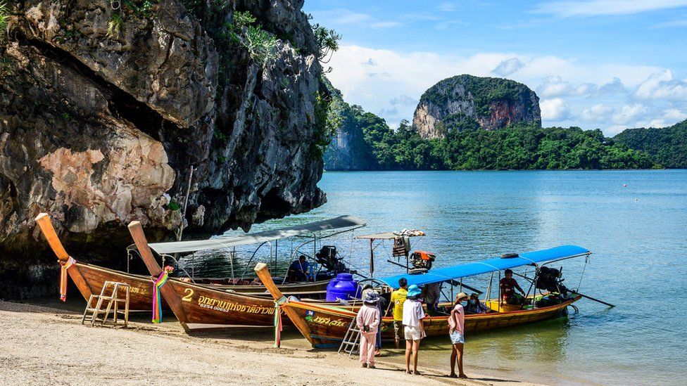 Beautiful Thai beach with boats and tourism staff.