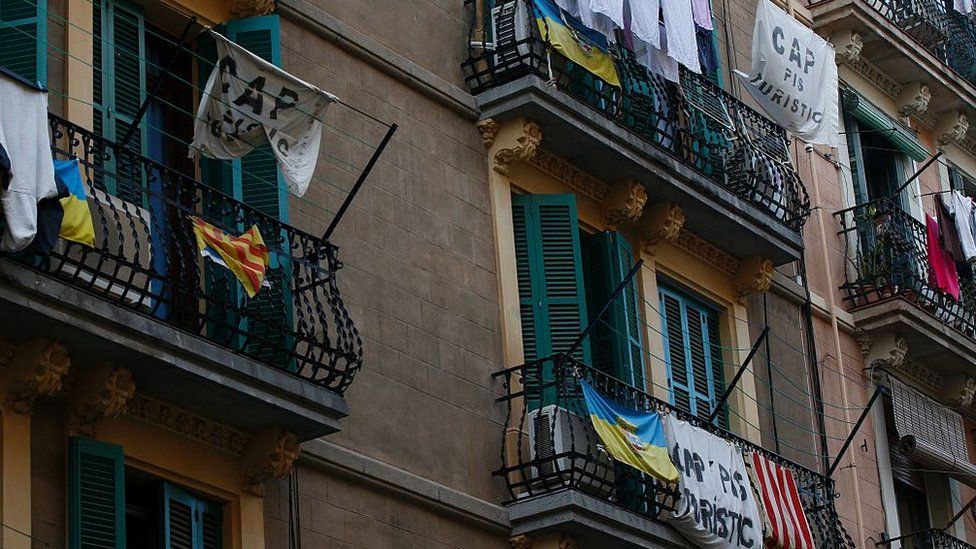 Banners reading 'No tourist flats' hang from a balcony to protest against holiday rental apartments for tourists in Barcelona's neighbourhood of Barceloneta