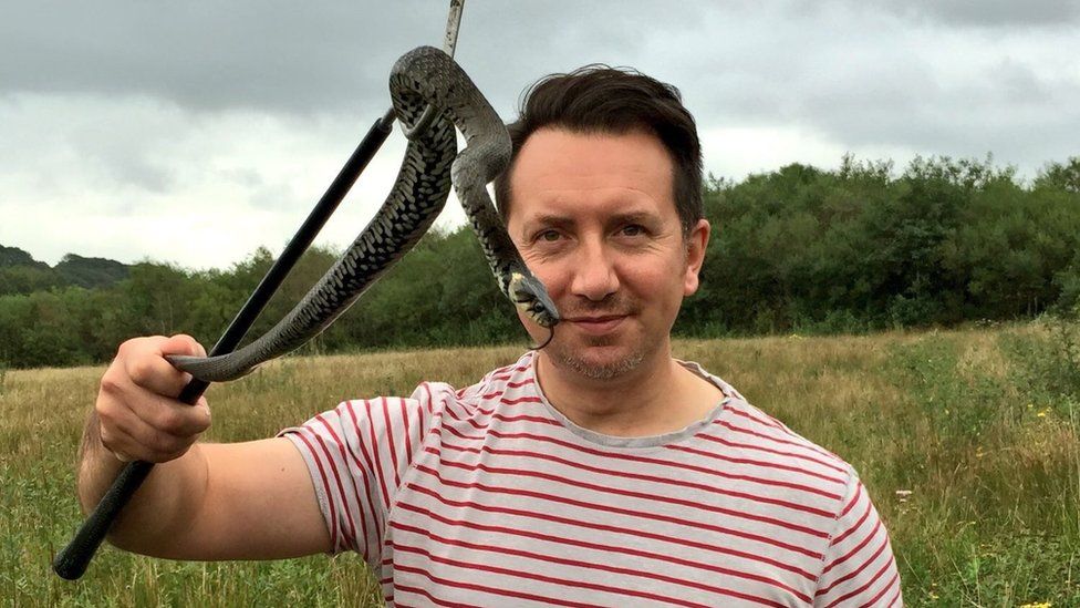 Dr Rhys Jones having his photo taken with a snake on a stick