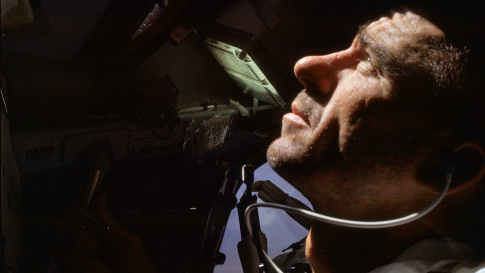 Уолтер Каннингем смотрит в окно космического корабля