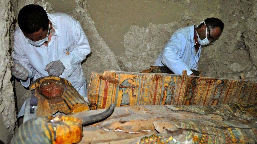 Two men in masks working on colourful coffins