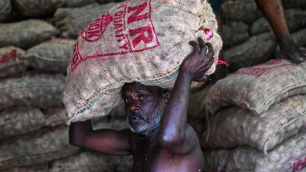 A labourer carries a sack of onions at a market in Colombo.
