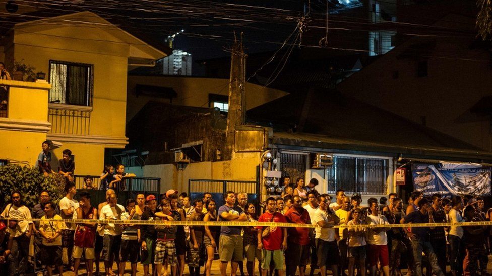 Residents of a Manila district at the scene of a shootout that left two suspected drug dealers dead