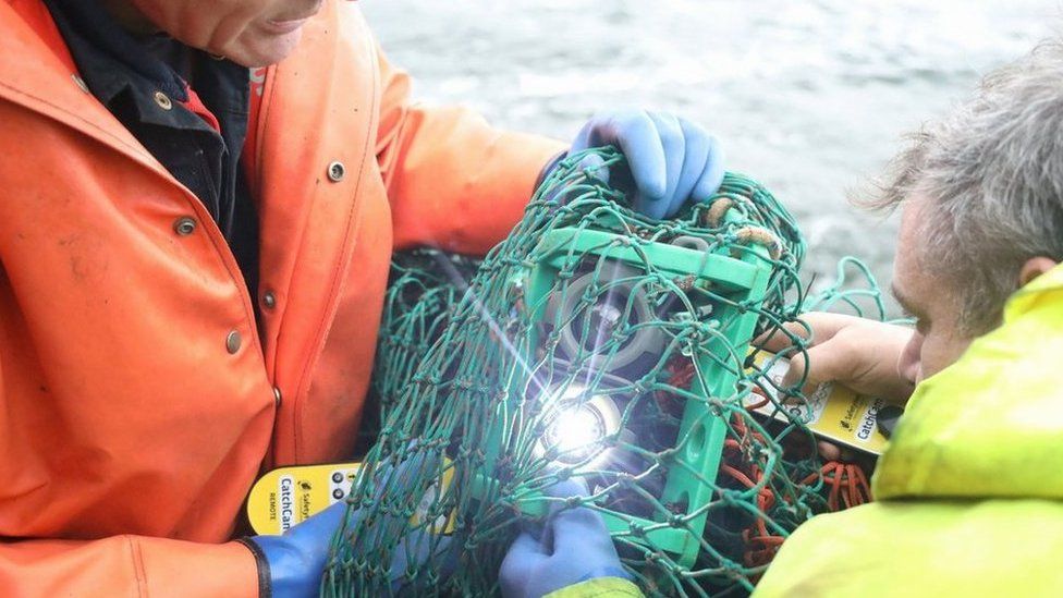 Two fishermen holding camera technology