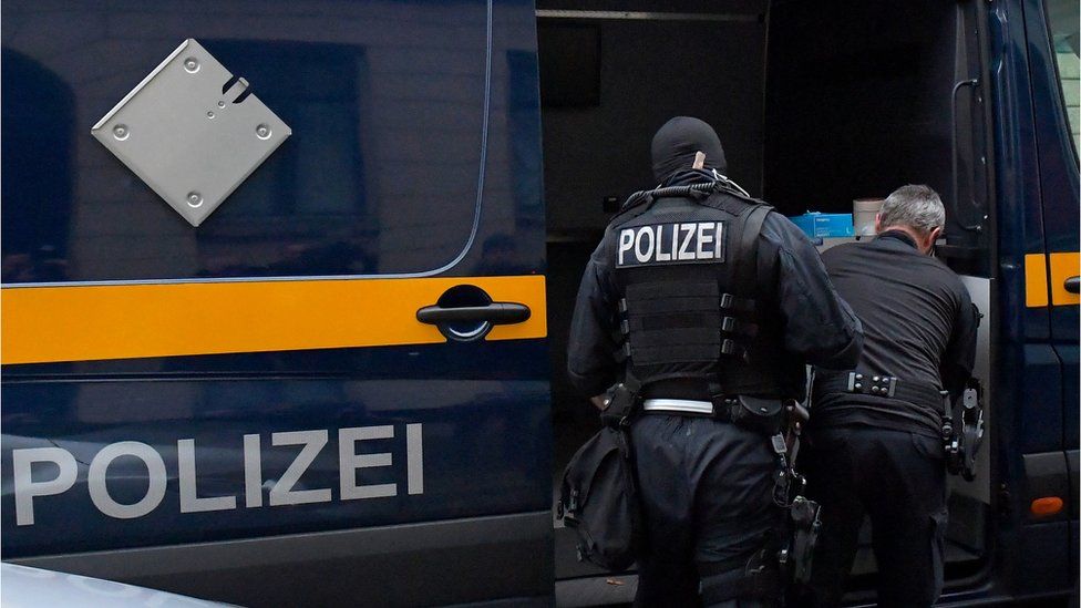 Police in front of a vehicle during raids in several locations in Dresden, Germany, December 15, 2021
