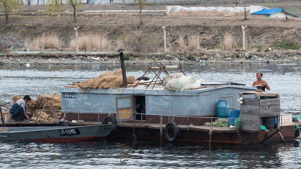 North Koreans on a boat as seen on the Yalu river, Qingcheng