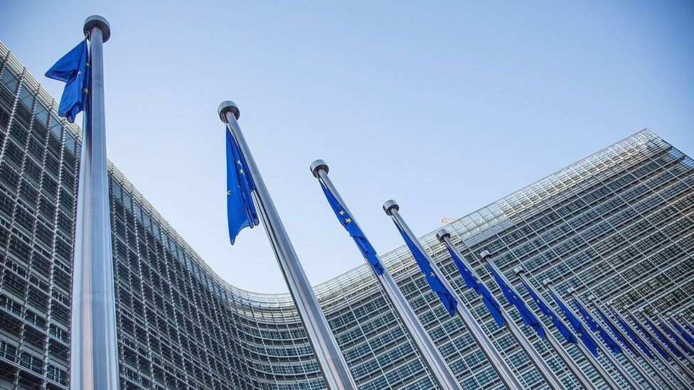 A view of European flags in front of the European Commission headquarters at the Berlaymont Building in Brussels