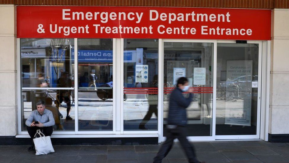 A man wearing a protective face mask walks past the Emergency Department and Urgent Treatment Centre entrance to Chelsea and Westminster hospital in central London, March 23, 2020,