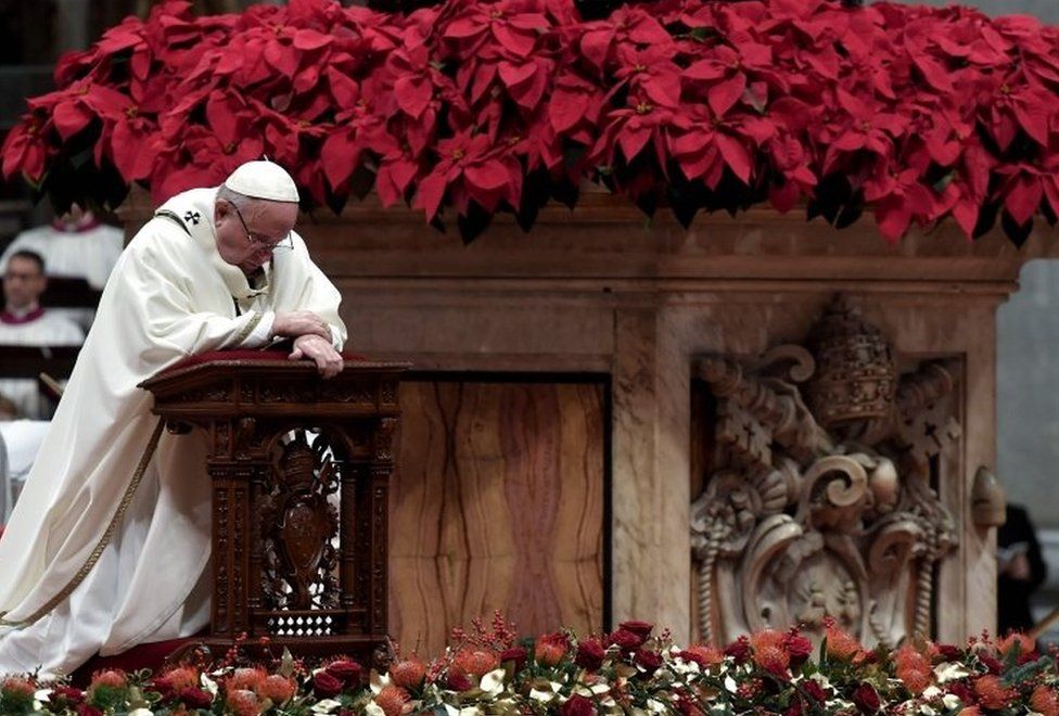 Pope Francis kneels down to pray during a Christmas Eve mass to mark the birth of Jesus Christ at St Peter's Basilica in the Vatican