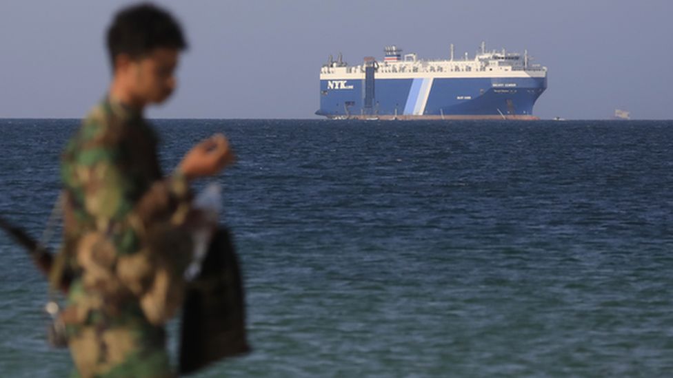 A Houthi soldier walks through the beach with the Galaxy Leader cargo ship in the background, seized by the Houthis offshore of the Al-Salif port on the Red Sea in the province of Hodeidah, Yemen, 05 December 2023.