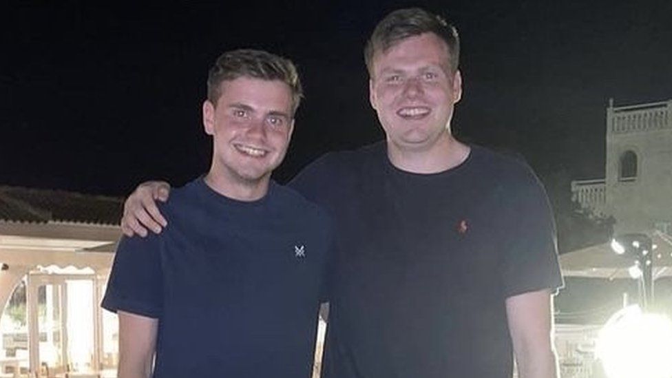 Brothers Jack and Ben O'Sullivan. Jack is 23 and Ben 27. The brothers are white men with cropped mousey brown hair. Ben is slightly taller than his younger brother. They're pictured on holiday at night, smiling at the camera with Ben's arm around Jack's shoulders.
