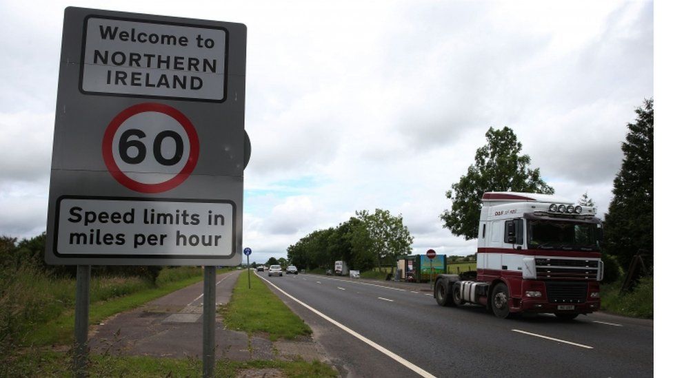 A lorry crosses the border from Northern Ireland to the Republic of Ireland passing a road sign welcoming drivers to Northern Ireland.