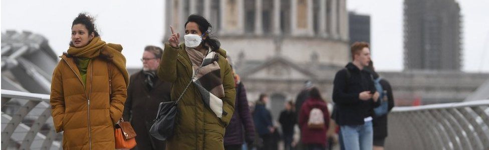 People in masks walking in London
