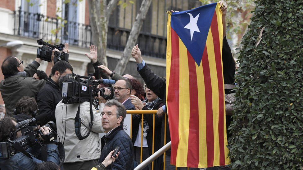 A protester holds a pro-independence Catalan Estelada flag next to journalists as members of the deposed Catalan regional government arrive at the National Court