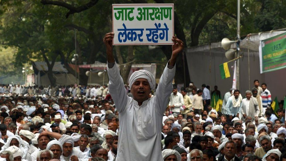 Член индийской общины джат держит плакат, гласящий, что его община получит статус резервации от правительства на акции протеста за расширение прав в Нью-Дели 2 марта 2017 года.