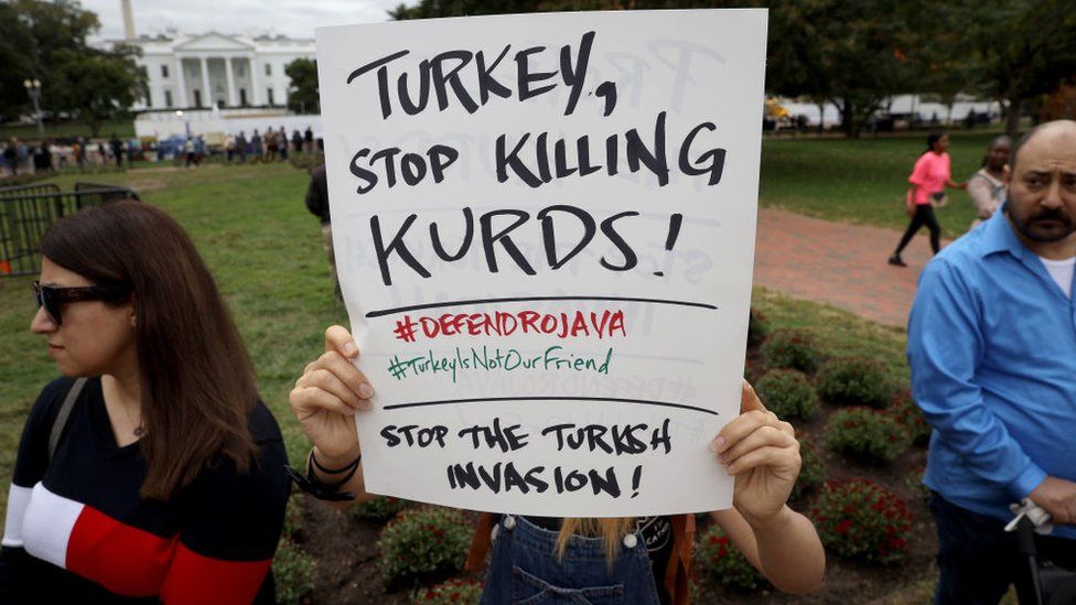 Protesters against Turkey's cross-border offensive in northern Syria wave signs outside the White House in Washington DC