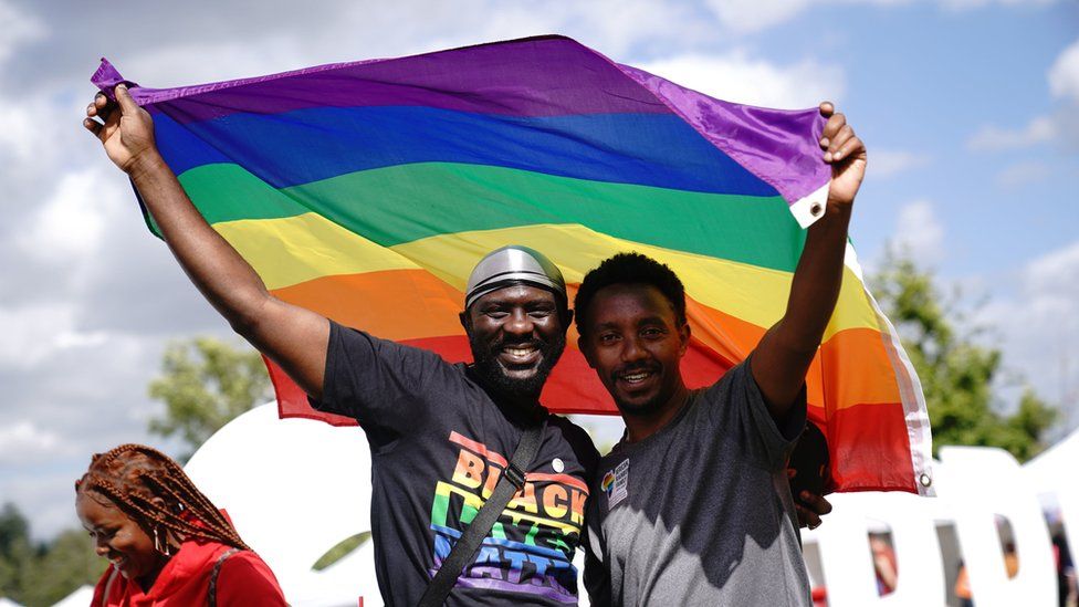Attendees smile and hold a flag at UK Black Pride