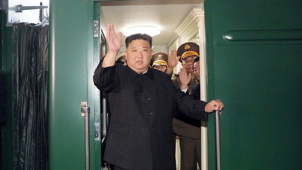Г-н Ким машет рукой из своего частного поезда перед отъездом из Пхеньяна, Северная Корея, в Россию