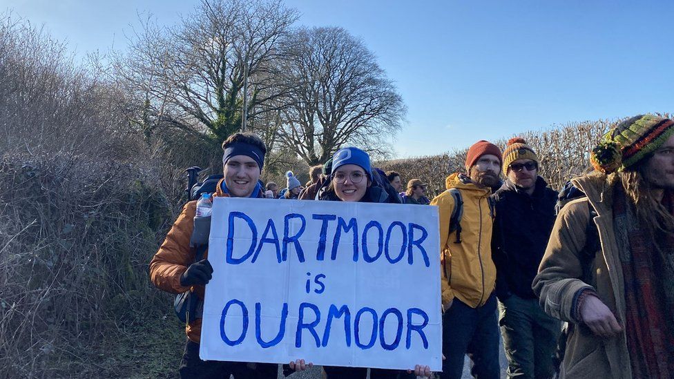 Young couple hold a sign that says "Dartmoor is Our Moor"