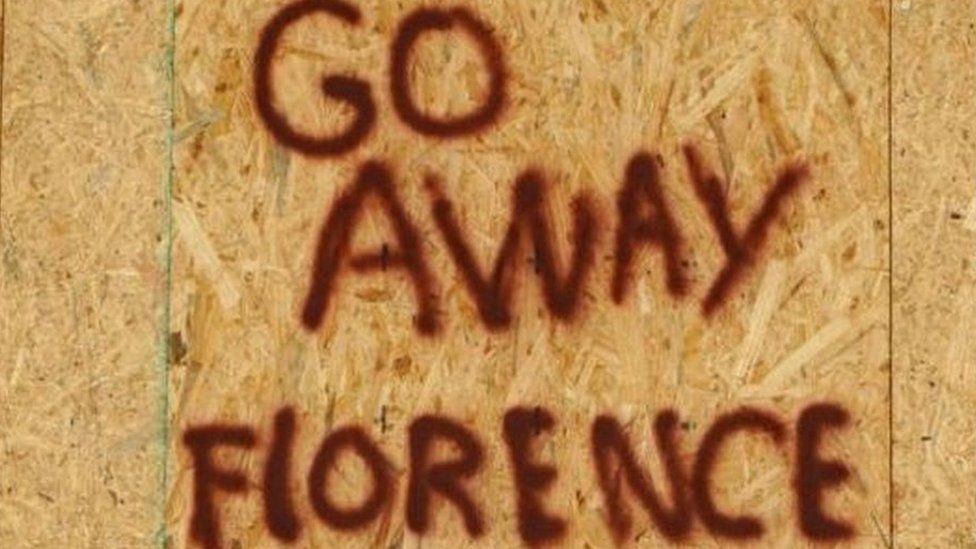 A sign on a boarded-up building reads "Go away Florence"