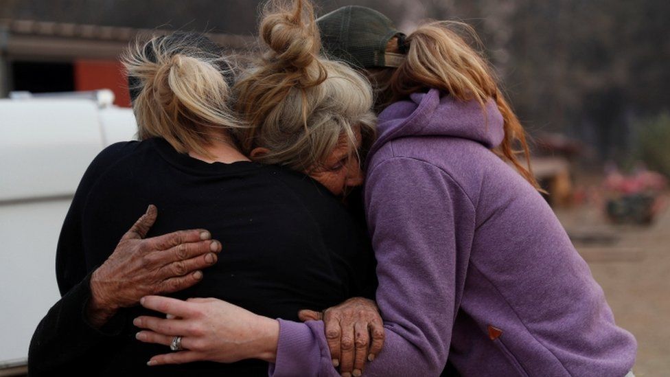 Three women affected by fire comfort each other