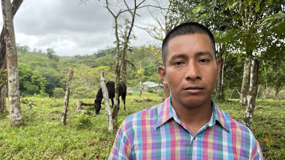 Farmer Diego Herrera is pictured on his farm, in front of some trees, a fence and a black horse