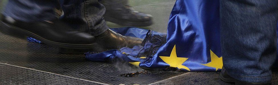 Protesters trample a burnt European Union flag during a demonstration untitled 'To be members, or to be free?' and called by the right-wing parliamentary party 'Jobbik' against European Union in front of the European Union Parliament and Committee headquarters in downtown Budapest on January 14, 2012