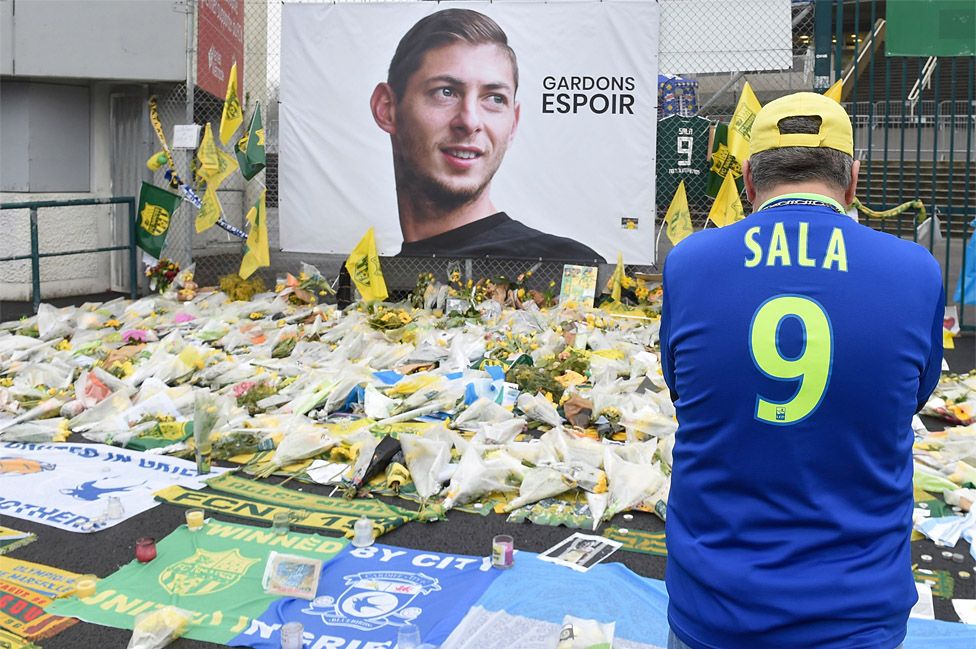 A supporter stands in front of flowers placed in front of a giant portrait of Emilianio Sala outside La Beaujoire stadium before Tuesday's French Cup match between FC Nantes and Toulouse FC