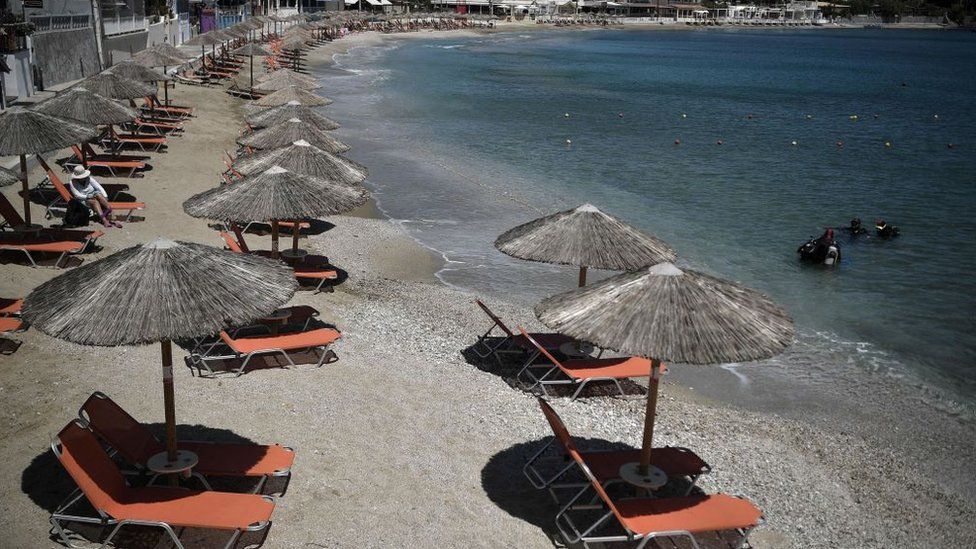 A picture taken on May 14, 2021 shows umbrellas on a beach prepared for tourists at Aghia Pelagia, near Heraklion on the island of Crete