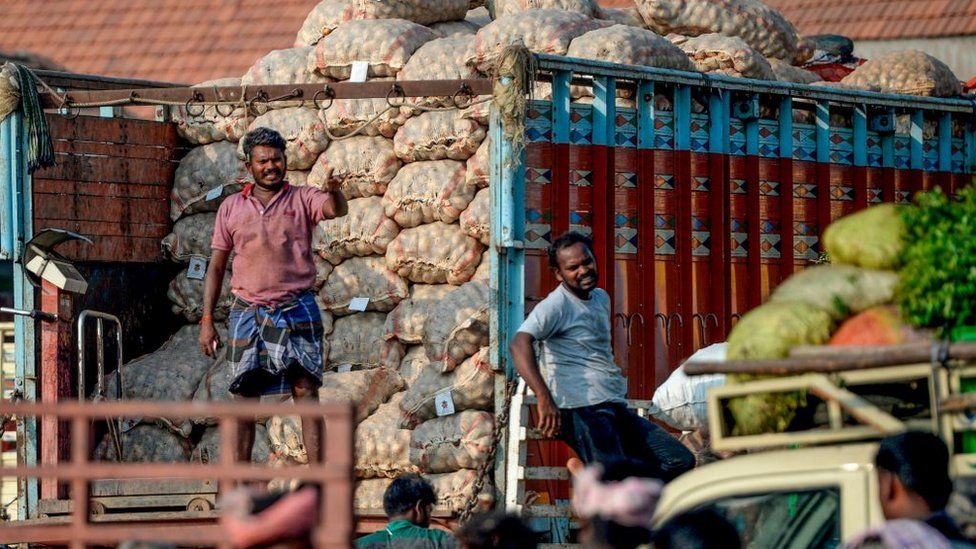 Labourers look on as they unload vegetable bags at a wholesale vegetable market in Chennai on February 1, 2020.