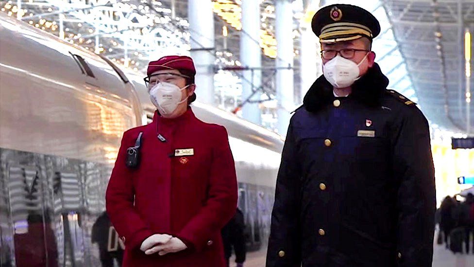 Train attendants stand next to a high speed train in Beijing