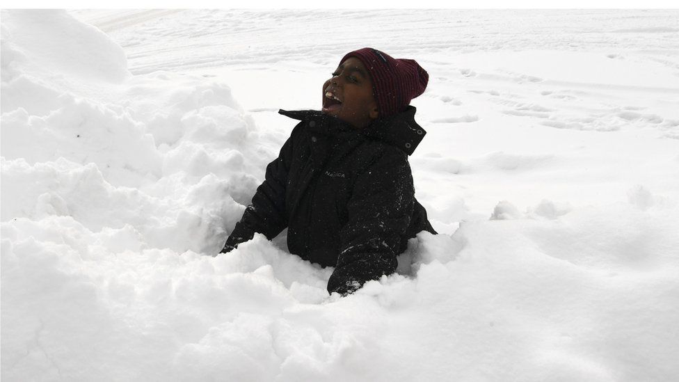 A boy smiles and plays in the snow