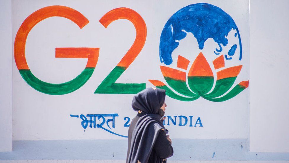 A Kashmiri woman walks in front of a sign ahead of the G20 summit on May 21, 2023 in Srinagar, Indian administered Kashmir, India. The Group of Twenty (G20) is the premier forum for economic cooperation worldwide.