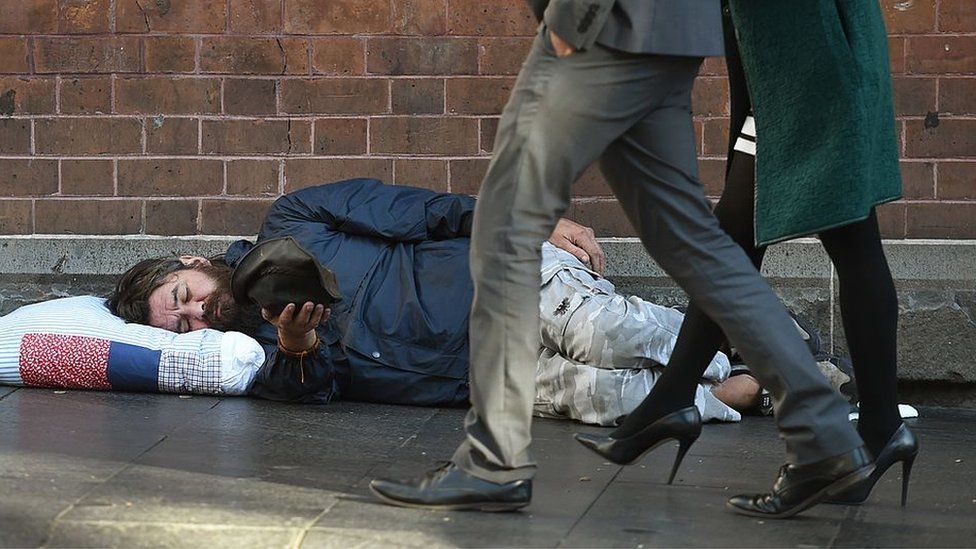 A homeless man begs on the pavement in Sydney's Central Business District