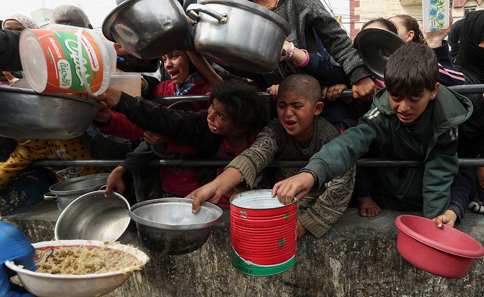 Palestinian children wait to receive food cooked by a charity kitchen in Rafah, in southern Gaza.