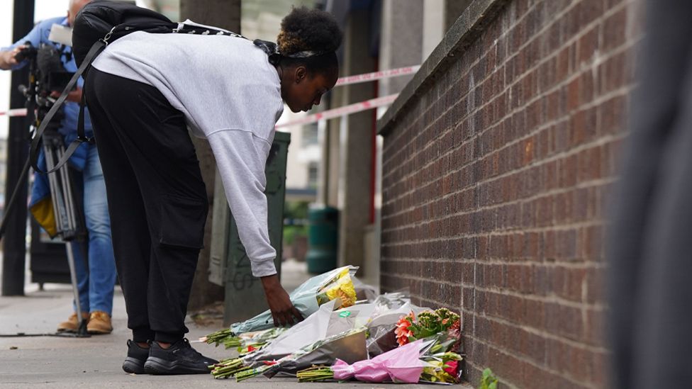 A girl lays flowers at the scene in Croydon
