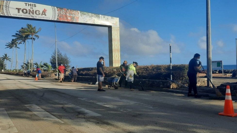 Люди убирают мусор после извержения вулкана и цунами в Нукуалофе, Тонга, на этой фотографии, полученной из социальных сетей 20 января 2022 года.