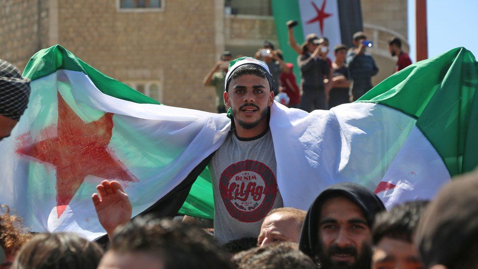 Syrian protesters wave their national flag as they demonstrate against the regime and its ally Russia, in the rebel-held city of Idlib on September 7, 2018