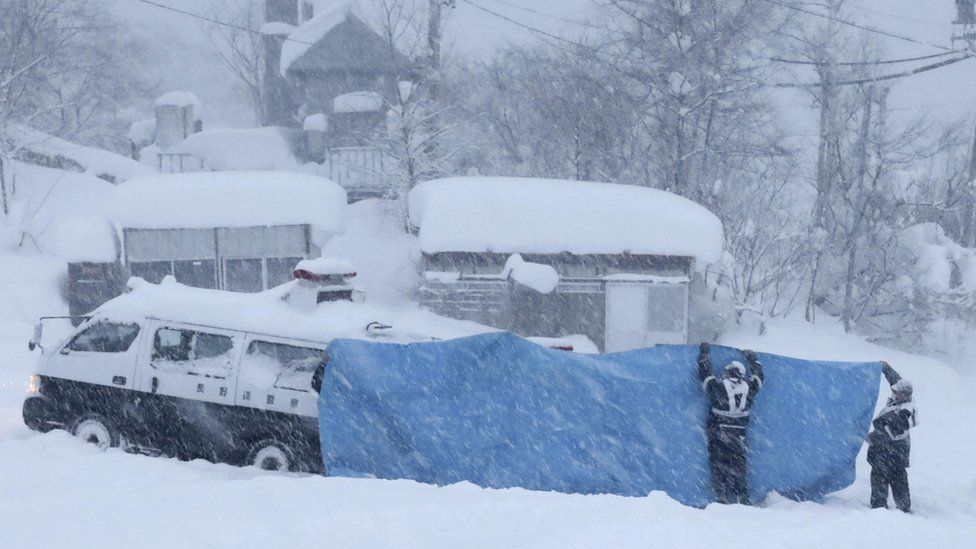 Полицейские пытаются транспортировать пострадавших, найденных на месте происшествия после схода лавины накануне, в деревне Отари в префектуре Нагано, центральная Япония, 30 января 2023 г.