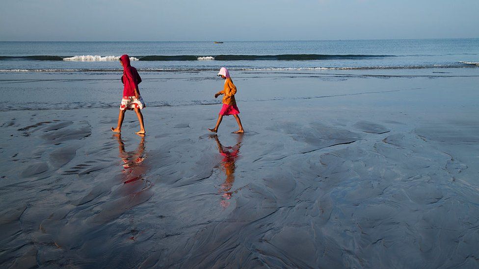 Locals walking across Ashvem Beach, Mandrem, Goa, India during sunset on November 28, 2014.