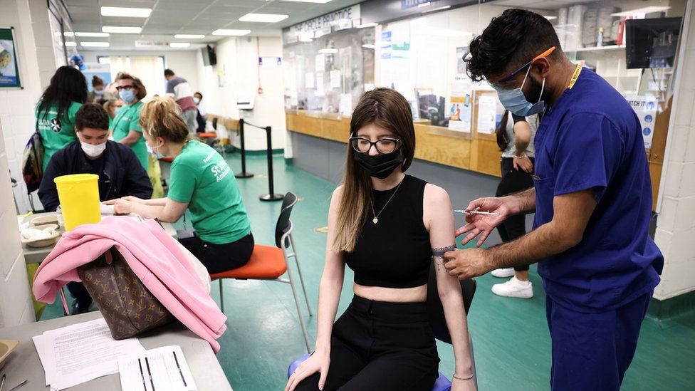 A person receives a dose of the Pfizer-BioNTech vaccine at a vaccination centre for those aged over 18 years old at the Belmont Health Centre in Harrow