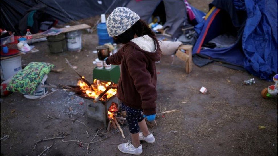 A Mexican girl tries to warm herself by a fire as temperatures dropped in Ciudad Juarez