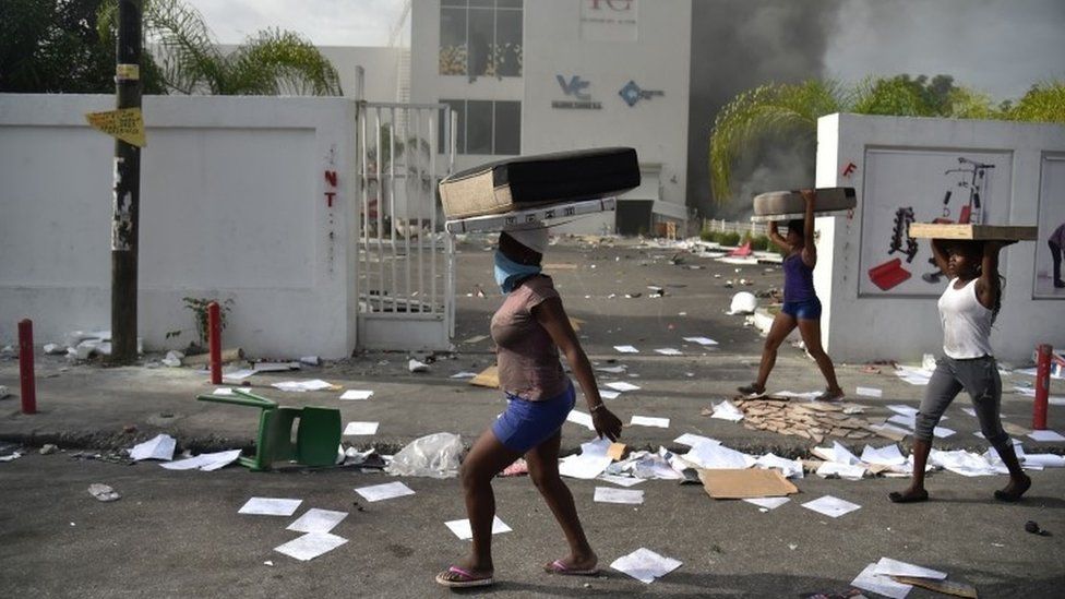 In this file photo taken on July 7, 2018 People carry loot from a shop in the commune of Petion Ville during protest against the increase in fuel prices, in Port-au-Prince.