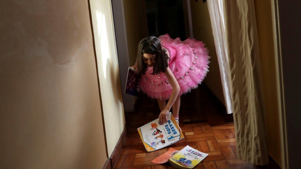 Menina de 5 anos com seus livros escolares e de literatura em Santo André (SP), em meio à quarentena