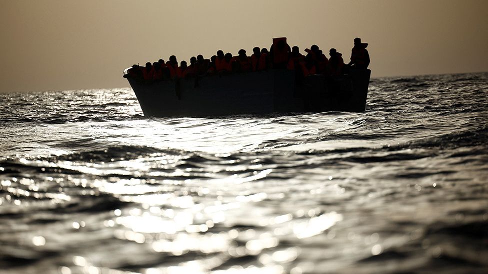 Мигранты (в силуэте) ждут в лодке во время поисково-спасательной операции спасательного катера НПО Proactiva Open Arms Uno в центральной части Средиземного моря, 17 августа 2022 г.