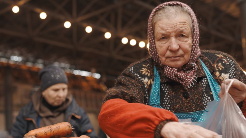 A Moldovan woman puts carrots in a bag