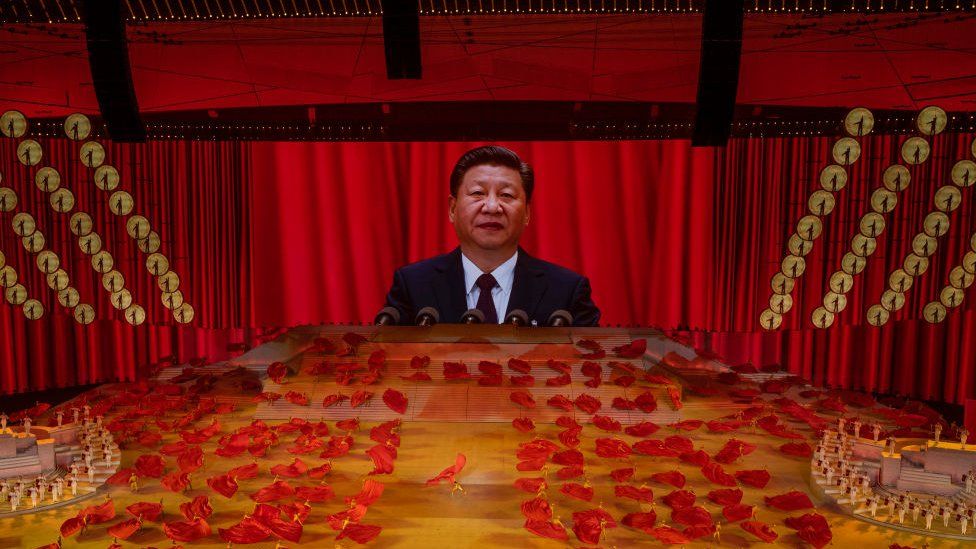 Президент Китая и председатель Коммунистической партии Си Цзиньпин появляется на большом экране, когда артисты танцуют во время массового гала, посвященного 100-летию коммунистической партии 28 июня 2021 года.