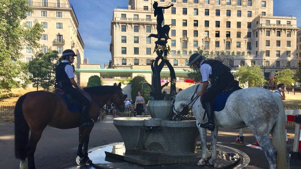 Police horses drink from a fountain in Greek Park, London.