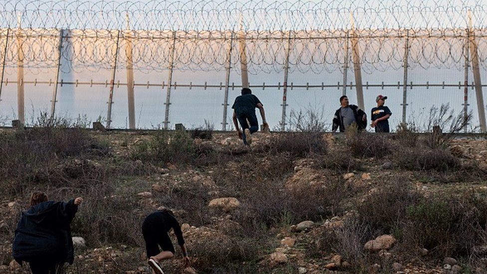 Migrants run after crossing the Mexico-US border fence in Tijuana, Mexico