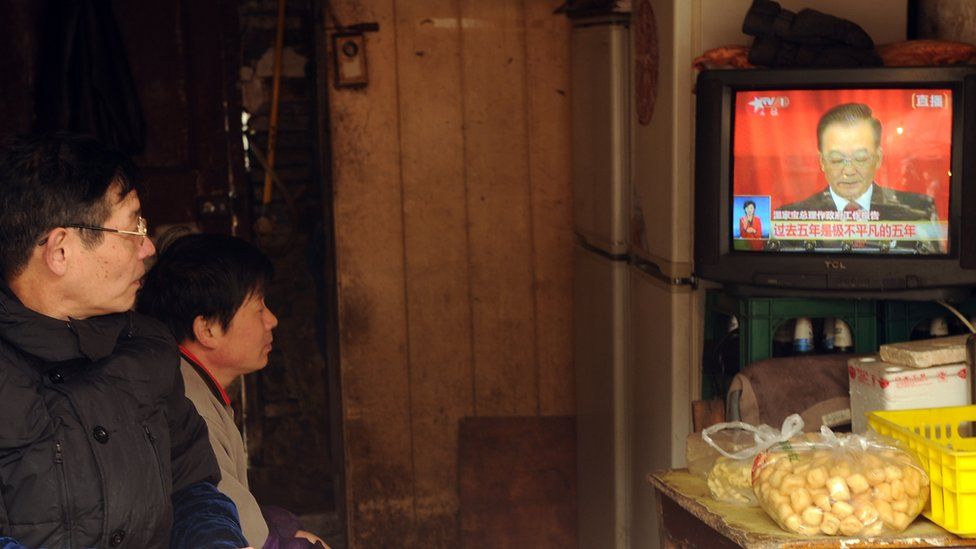 Two people watch a television set showing Chinese Premier Wen Jiabao